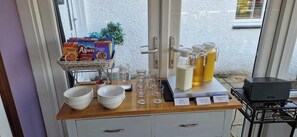 Ein Frühstücksbuffet mit Getreideboxen, Milch, Saft und Gläsern.