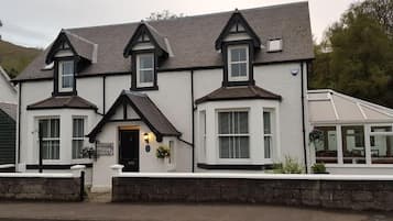 A two-story building with a traditional architectural style, featuring a prominent entrance with a black door and a sign above it.