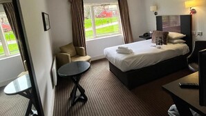 Een hotelkamer met een bed, een tafeltje, een bank en een bureau.