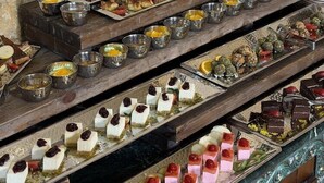 Un buffet proposant une variété de desserts et de petites portions, présentés sur des plateaux de service en bois.