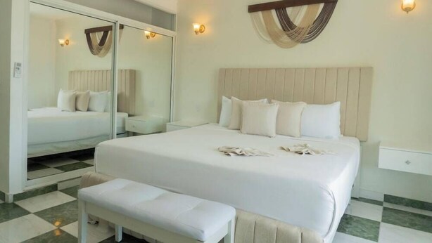 Een hotelkamer met een groot bed, een bankje, een spiegel en een wandlamp.