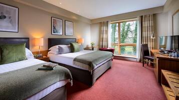 A hotel room with two beds, a desk, a chair, a TV, and a window with curtains.