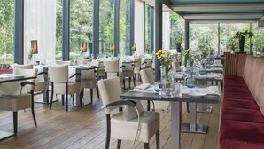 Ein Restaurant mit Innenbereich, Tischen, Stühlen und großen Fenstern sowie einer roten Bank.