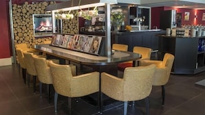 Eine moderne Bar mit einer gebogenen Theke, mehreren Barhocker und einem Fernseher, der ein Feuer zeigt.