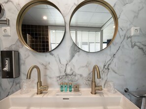 A bathroom with two round mirrors, a sink, and a towel rack. - Wageningen International Congress Centre (Wageningen)