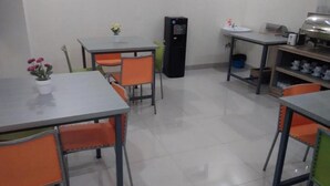 Un espace repas avec des tables et des chaises, un réfrigérateur, un évier et un buffet.