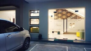 Un bâtiment moderne avec une façade en verre, une voiture garée devant et un escalier menant à un niveau supérieur.