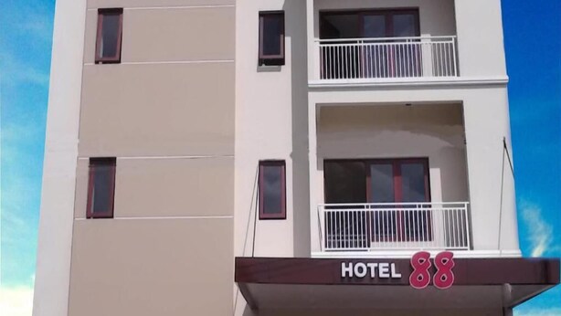 Un hôtel à plusieurs étages, doté de balcons et d’une enseigne indiquant « HÔTEL 88 ».