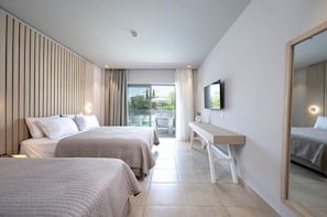 Habitació d'hotel amb dos llits, un escriptori, un televisor i un balcó amb mobiliari exterior.