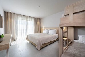 Una camera d'albergo con un letto grande, una scrivania con una pianta e un letto a castello.
