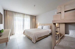 Habitación de hotel con una cama grande, un escritorio con una planta y una cama litera.