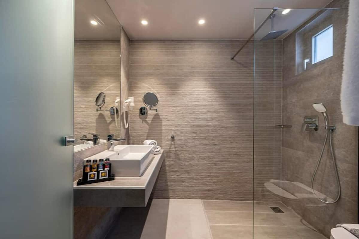 Un baño moderno con cabina de ducha de vidrio, una bañera grande y un tocador con espejo.