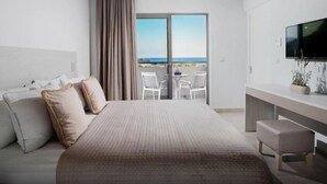 Ein modernes Hotelzimmer mit einem großen Bett, einem Fernseher, einem Balkon mit Meerblick und einem Schreibtisch.