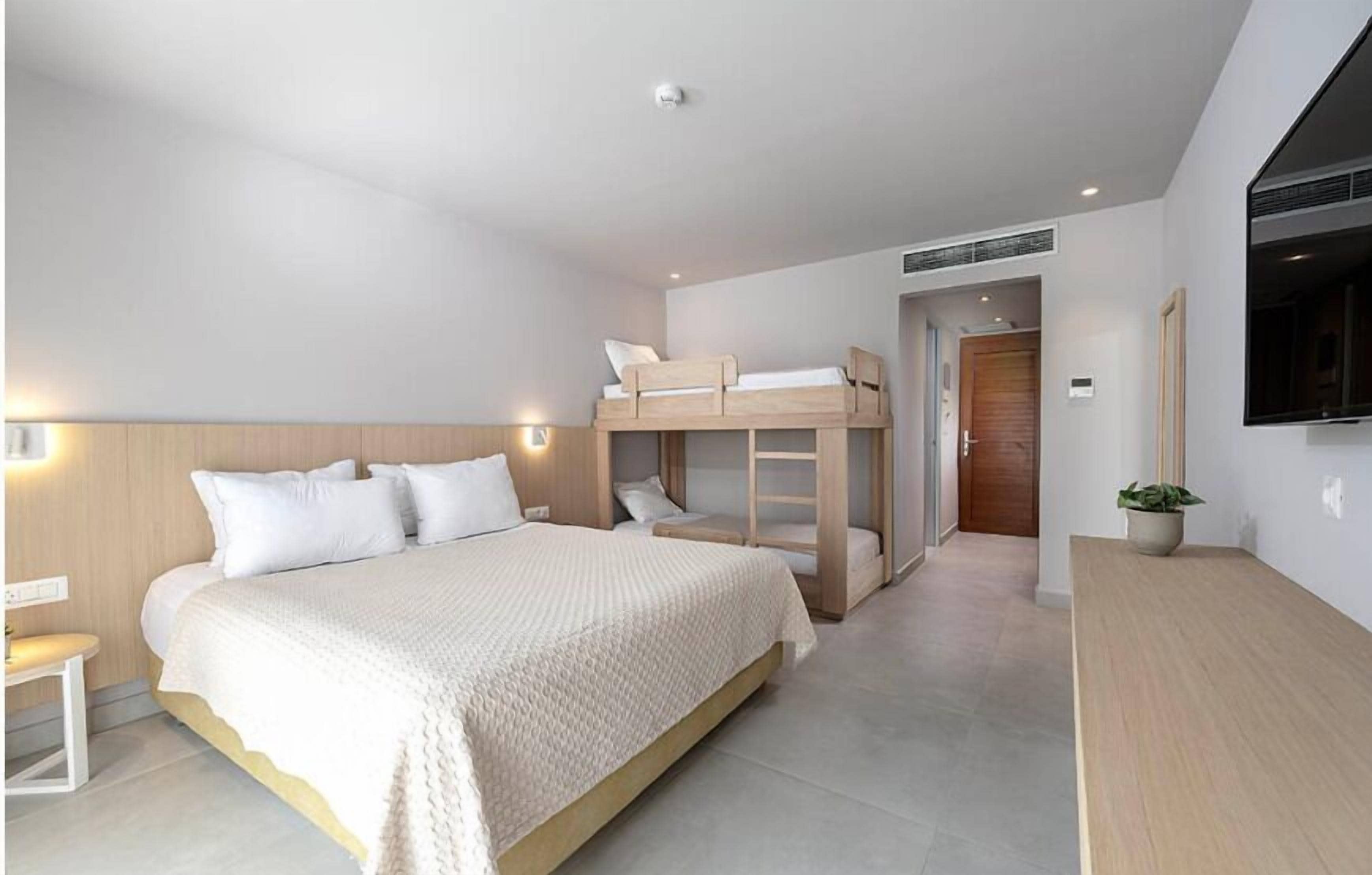 A bedroom with a bunk bed, a large bed, a bedside table, and a potted plant.