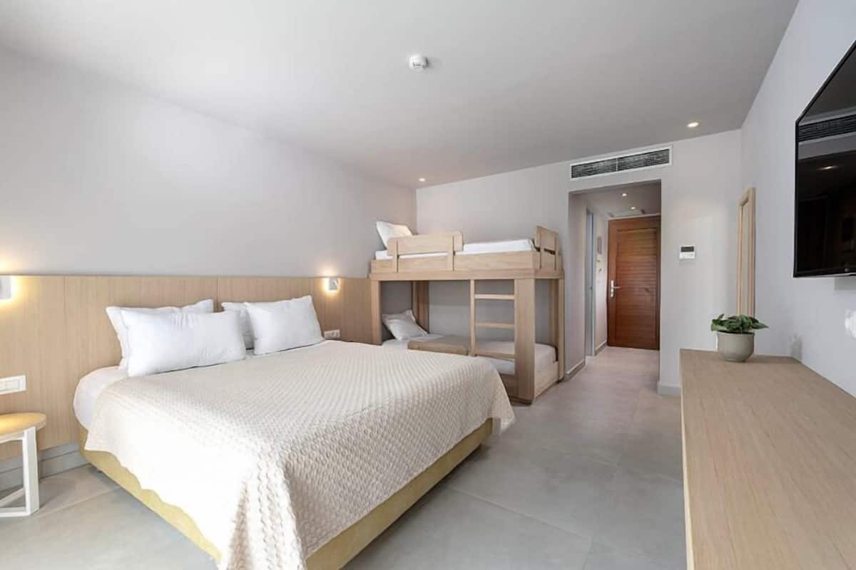 Un dormitorio con una litera, una cama grande, una mesita de noche y una planta en maceta.