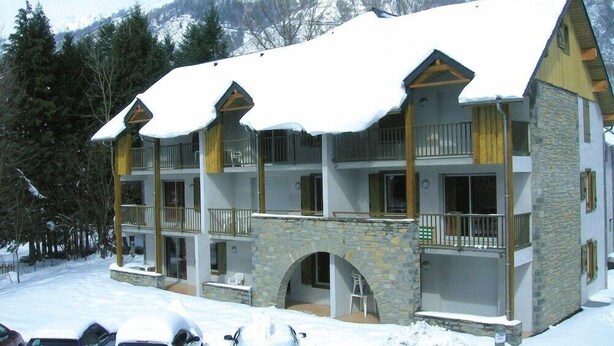 Een hotel met meerdere verdiepingen, een stenen gevel, balkons en een met sneeuw bedekte top.