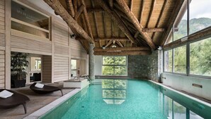 Een wellnesscentrum met houten inrichting, een zwembad en uitzicht op de bergen.