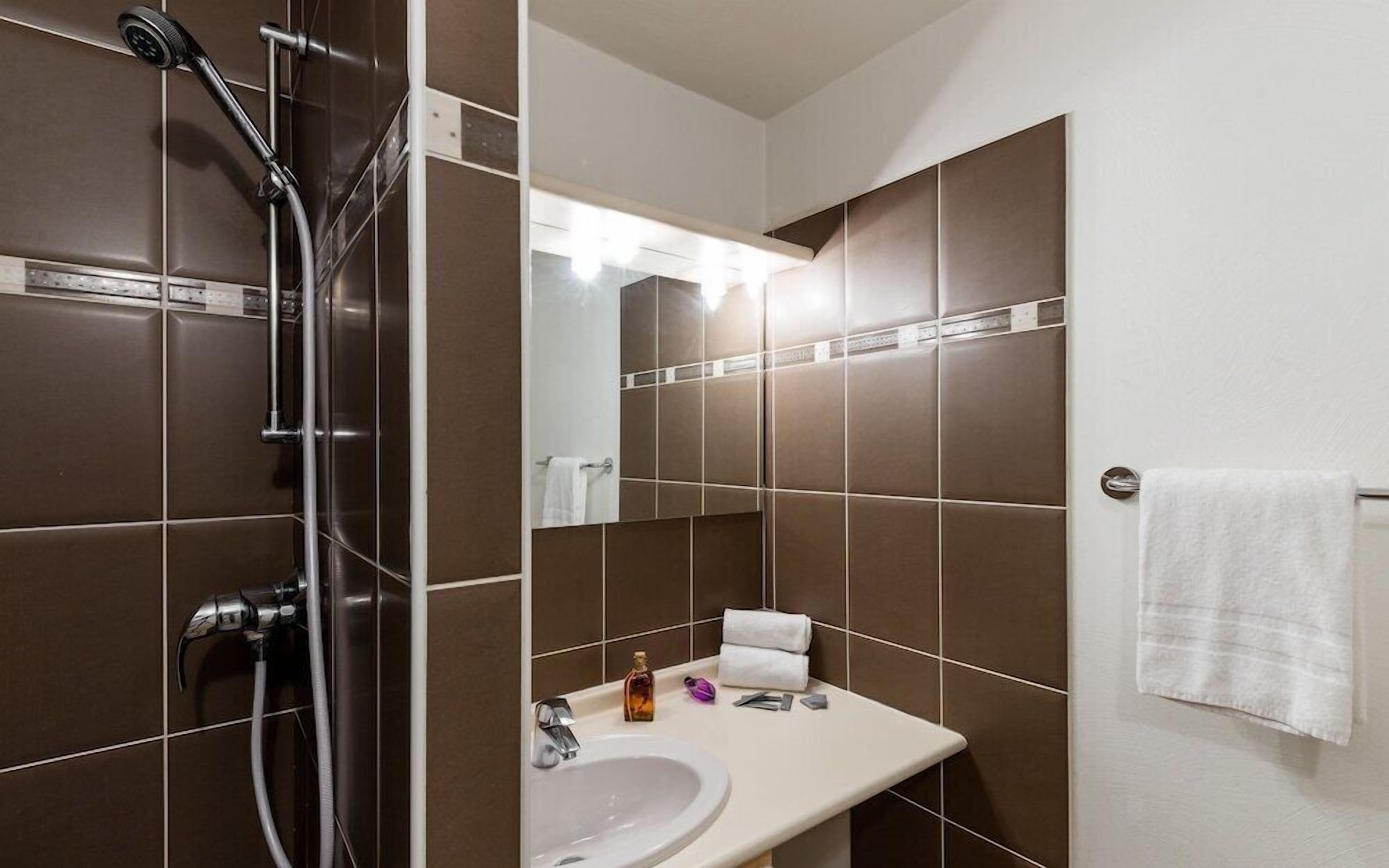Une salle de bain moderne équipée d’une douche, d’un lavabo et d’un porte-serviettes.