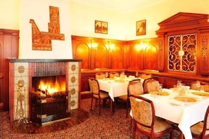 Comedor con chimenea, paneles de madera y mesas dispuestas para comer.