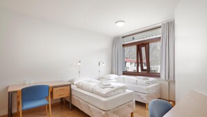 A room with a desk, two single beds, a chair, and a window with curtains. - Edda Hotel Isafjorour (Isafjordur)