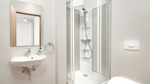 A modern bathroom with a white sink, a glass-enclosed shower, and a toilet. - Edda Hotel Isafjorour (Isafjordur)