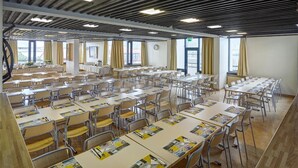 A spacious classroom with rows of desks and chairs, large windows, and a clock on the wall. - Edda Hotel Isafjorour (Isafjordur)