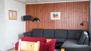 Un soggiorno moderno con un divano componibile, un tavolo da pranzo in legno e una sedia rossa.
