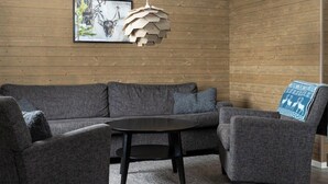 Un soggiorno moderno con un divano componibile, un tavolino rotondo e una lampada a sospensione in legno dal design originale.