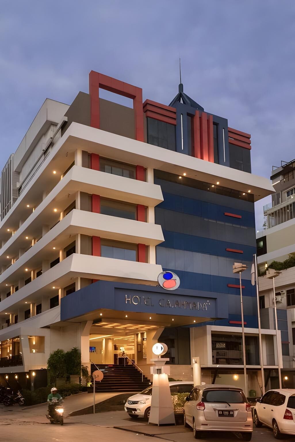 A multi-story hotel with a modern design, featuring balconies, a prominent entrance, and a sign indicating the hotel name.