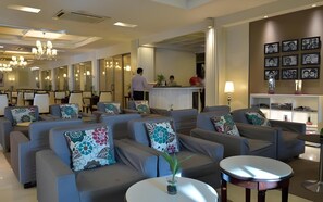 Een hotellobby met banken, een receptiebalie en een wand met ingelijste foto's.