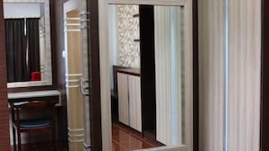 A room with a large mirror, a chair, and a wardrobe with a patterned door. - Pancur Gading Hotel And Resort (Petumbak)