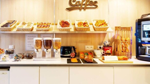Una estación de café con diversas opciones de pastelería y bocadillos, una máquina de café y una exhibición de pan.