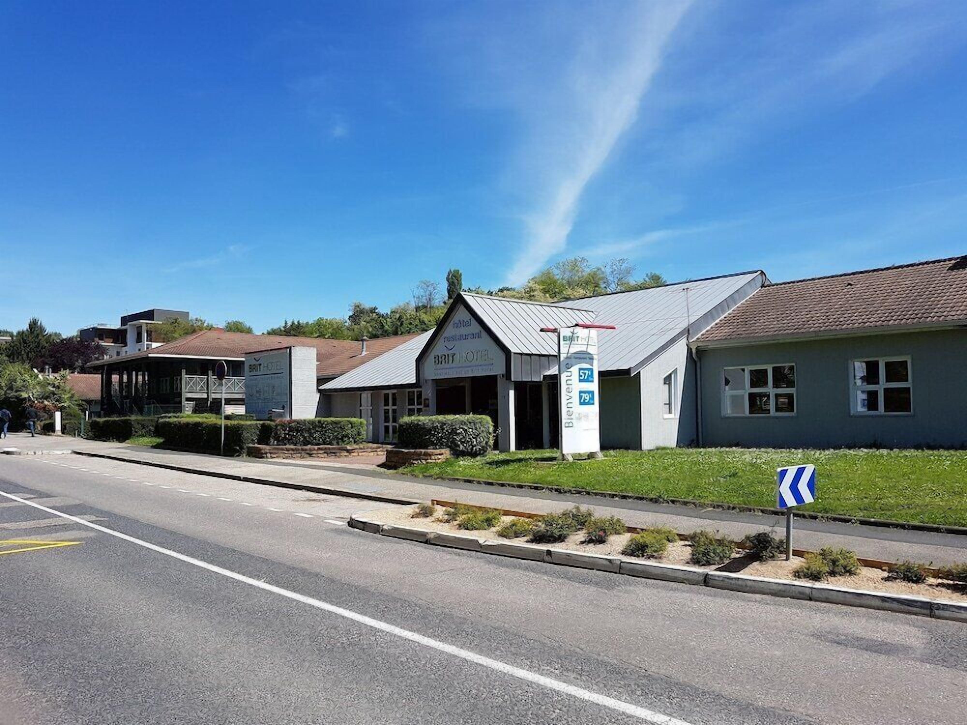 A hotel with a signboard, a road in front, and a blue directional sign.