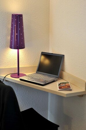 A laptop on a desk with a purple lamp. - Balladins Lyon Dardilly (Dardilly)