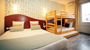 Ein Hotelzimmer mit Stockbett, einem Doppelbett und einer Wand mit Muster.