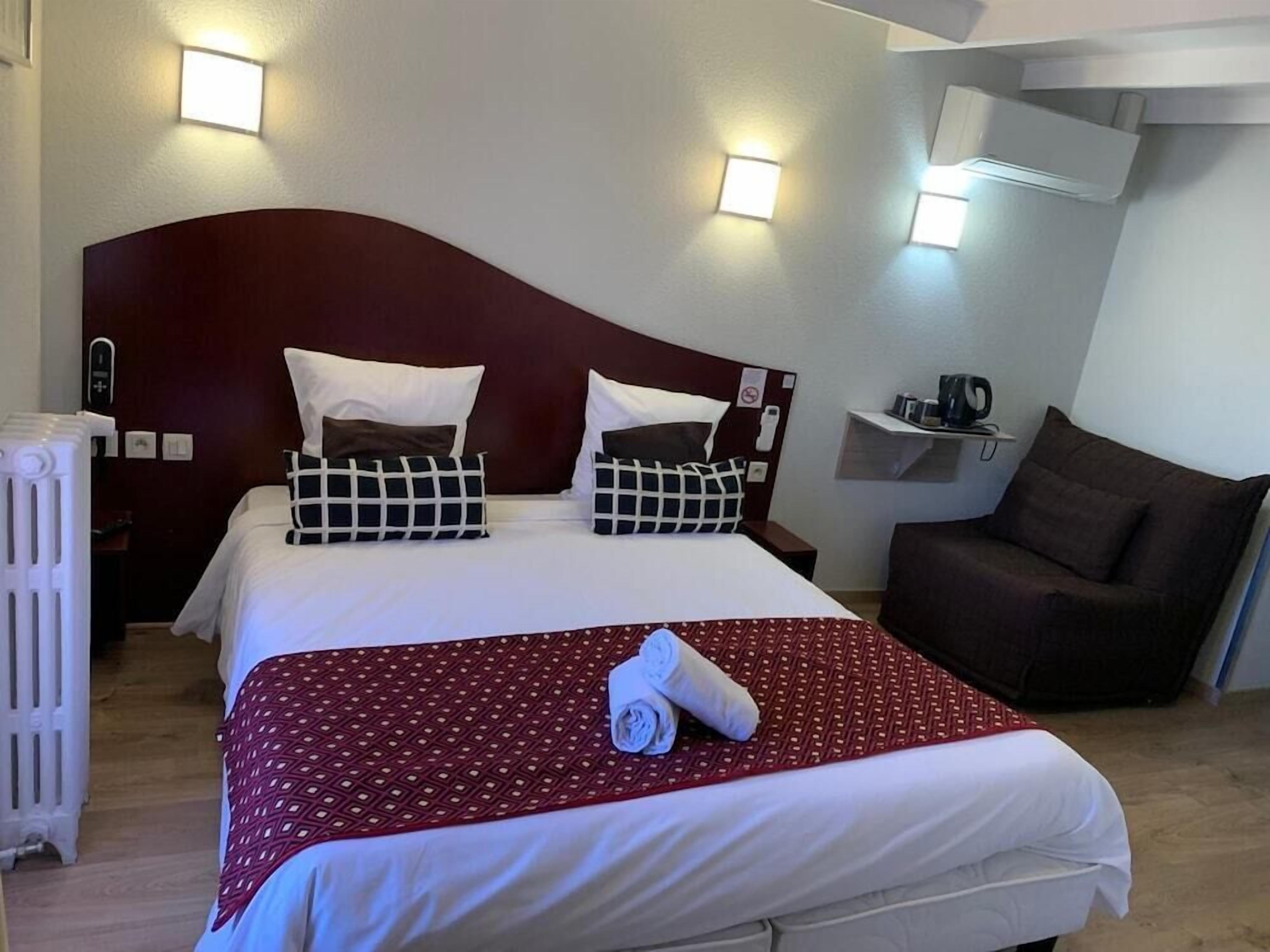 Habitación de hotel con una cama grande, dos mesitas de noche, una silla y un radiador.