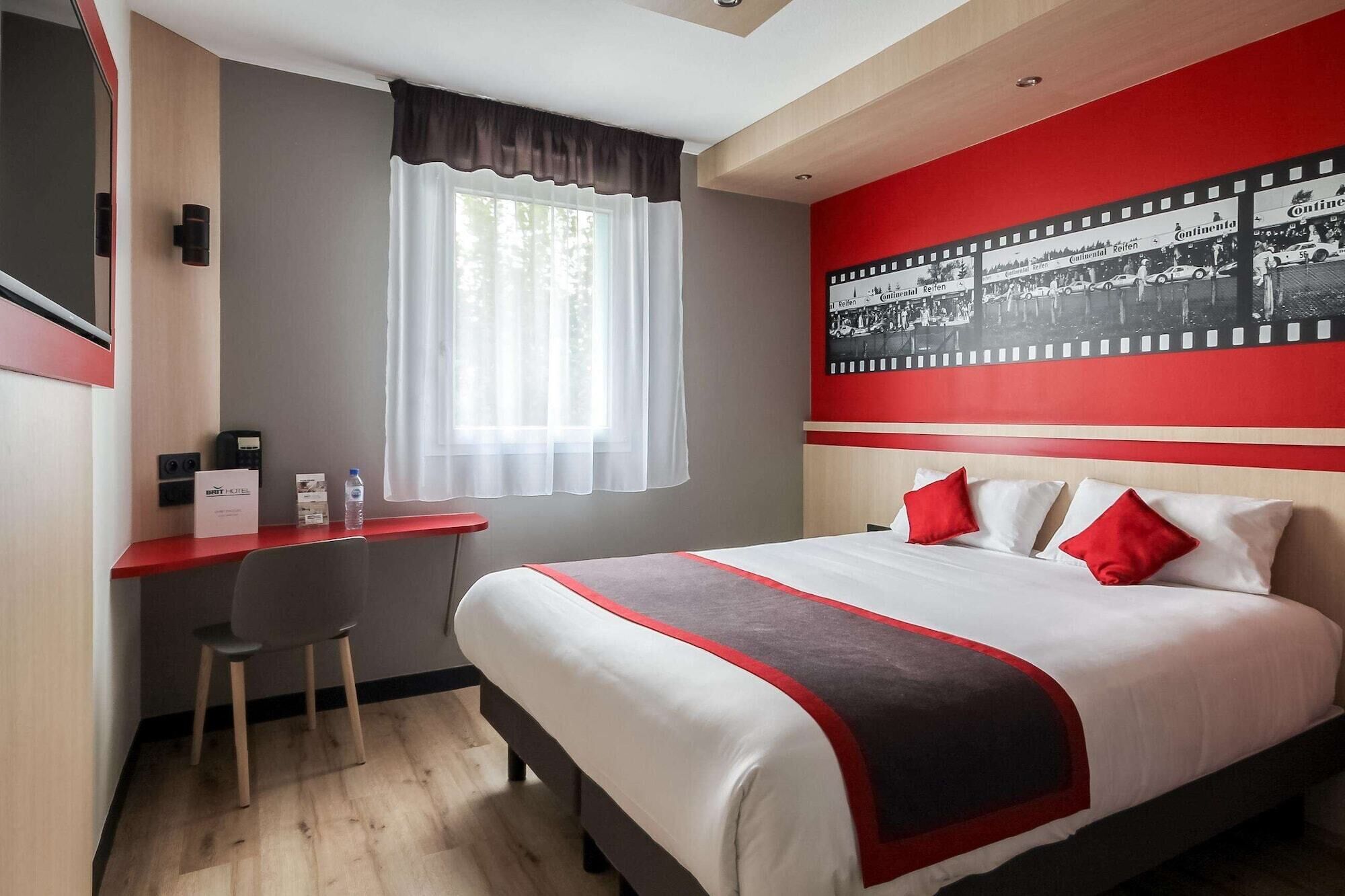 A hotel room with a bed, a desk, a chair, a window with curtains, and a wall with a filmstrip design.