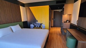 A modern hotel room with a large bed, a desk, and a seating area. - Brit Hotel Restaurant Le Cottage (Arnage)