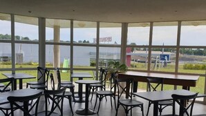 Amplio espacio interior con ventanas grandes que ofrecen vistas a un estacionamiento y un edificio con señalización.