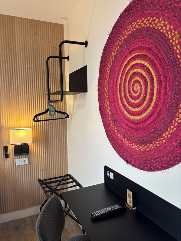 Une pièce moderne avec un mur lambrissé en bois, un bureau noir, une télécommande et une grande tapisserie circulaire tissée.