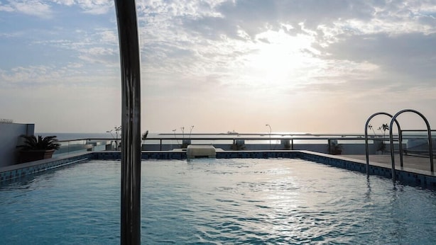 Une piscine avec vue sur le coucher de soleil et un pont en arrière-plan.