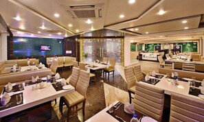 A modern restaurant with multiple dining areas, including booths and tables, and a visible restaurant sign. - Lords Eco Inn Porbandar (Porbandar)