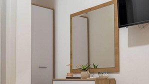 Un dormitorio con cama, cómoda, espejo y televisión.