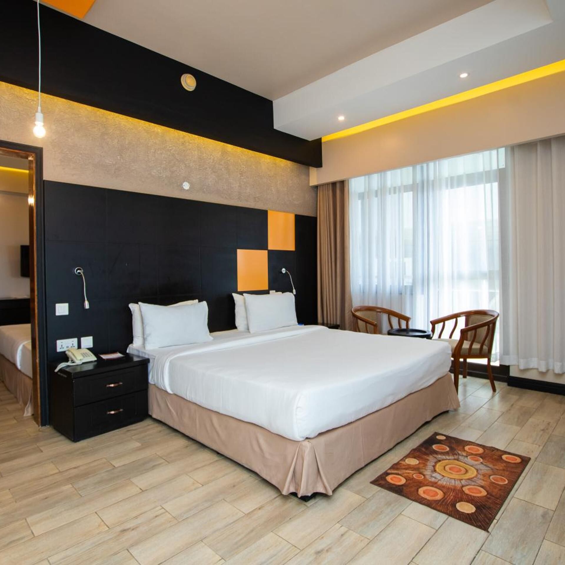 A modern hotel room with a large bed, bedside tables, a desk, and a chair.
