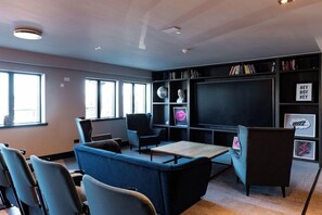 Un'area lounge moderna con posti a sedere, una grande TV a schermo piatto, scaffali e un camino.