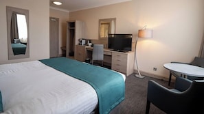 A hotel room with a bed, a desk, a chair, a TV, and a lamp. - Park (Kilmarnock)