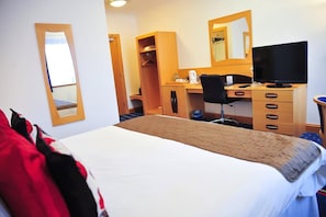 A hotel room with a bed, a desk with a computer, a chair, a wardrobe, and a mirror. - Park (Kilmarnock)