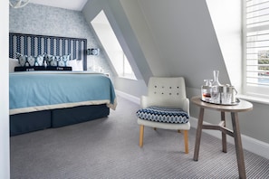 A bedroom with a bed, a chair, a small table with drinks, and a window with blinds. - The Fowey (Fowey)
