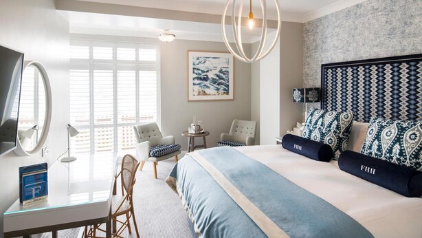 A modern hotel room with a large bed, a desk with a computer, a chair, and a TV. - The Fowey (Fowey)