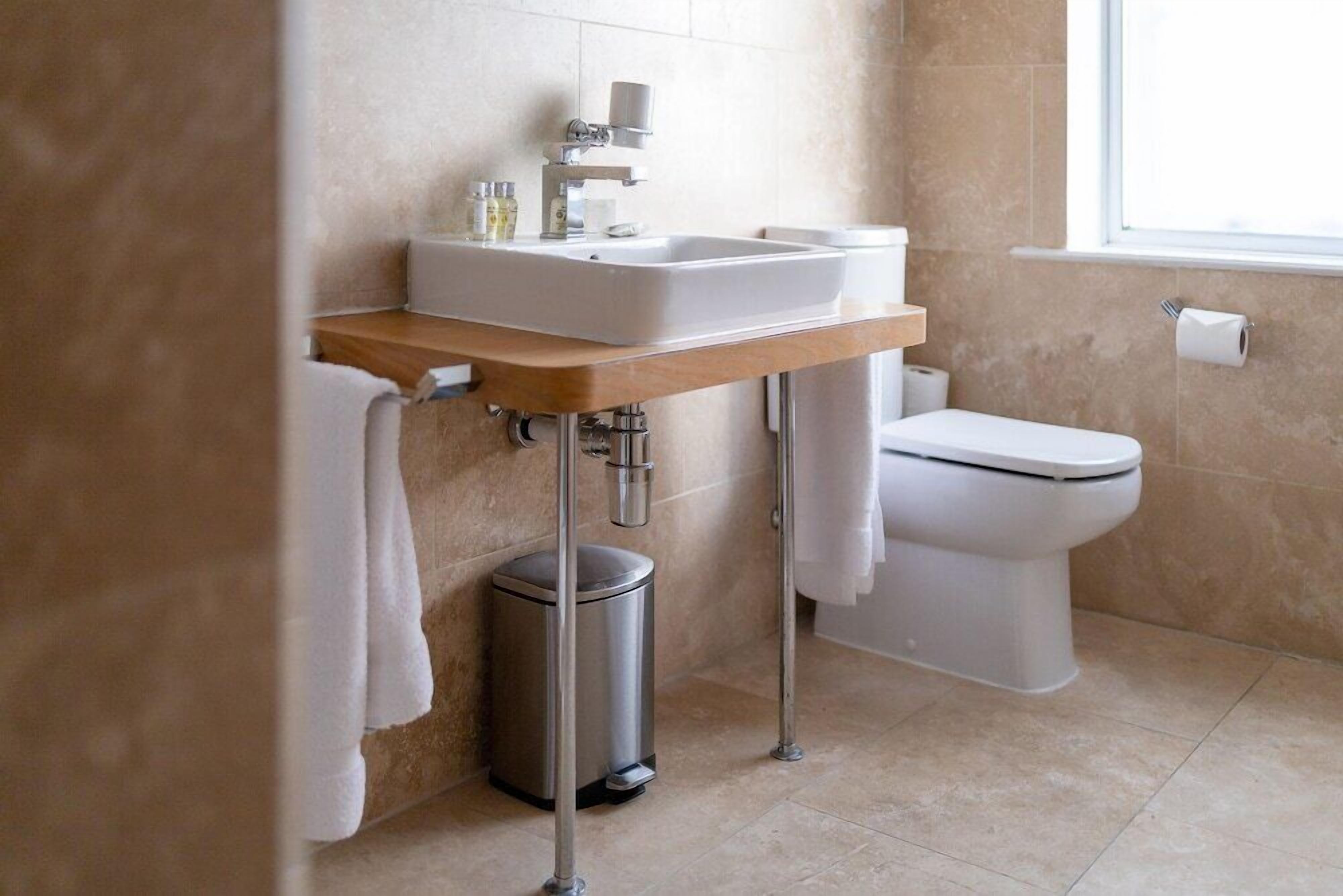 A modern bathroom with a sink, toilet, and trash can.